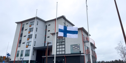 Suomen lippu puolitangossa kerrostalon pihalla